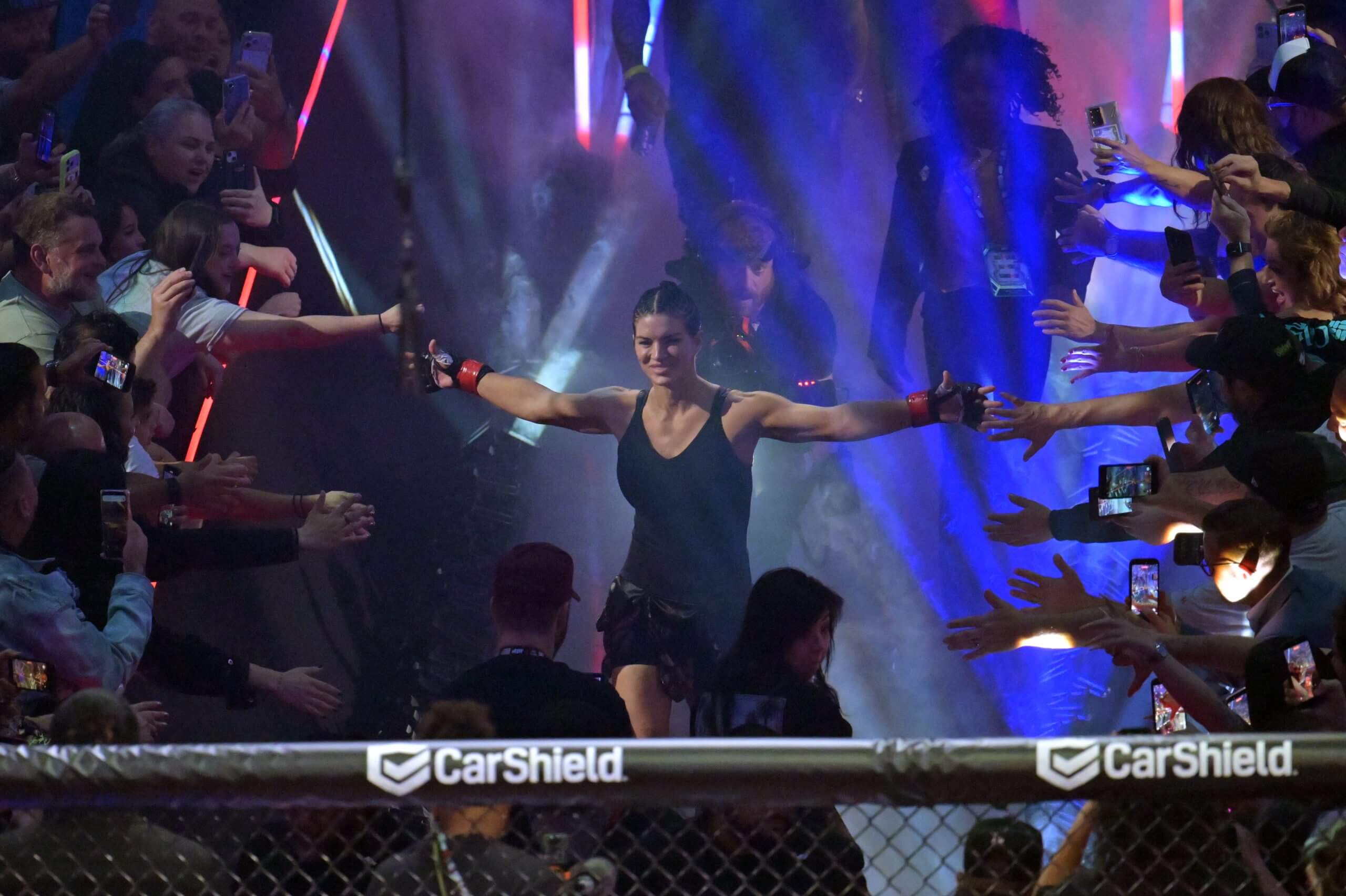 Gina Carano — with her arms extended to high-five fans reaching out to her — is introduced before fighting Ronda Rousey.