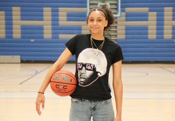 Headshot of Aaliyah Douglas holding a basketball in Albany High gym