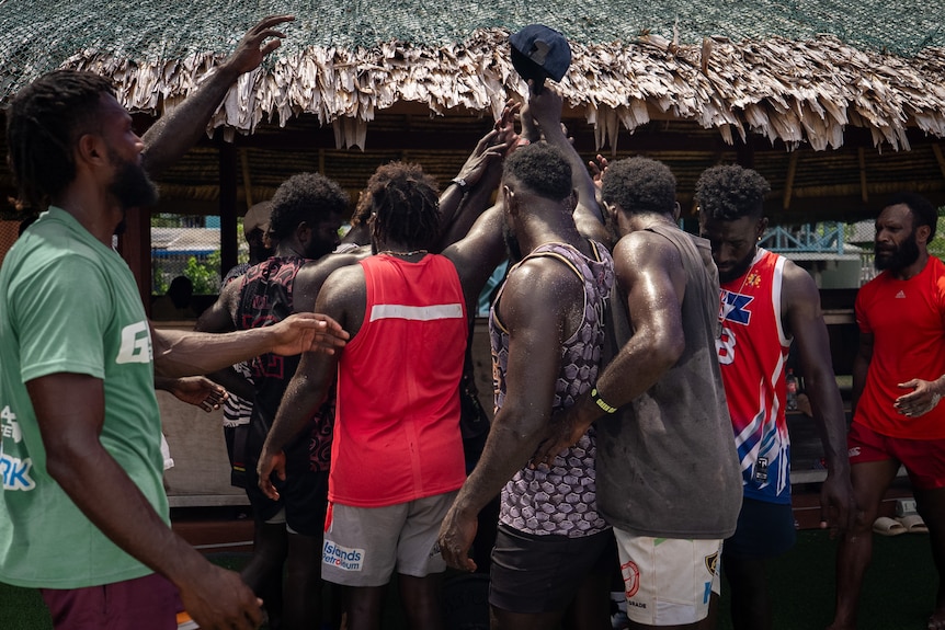 A photo of Bougainville rugby players in a huddle.