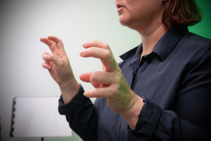 A woman gesturing in Auslan. 
