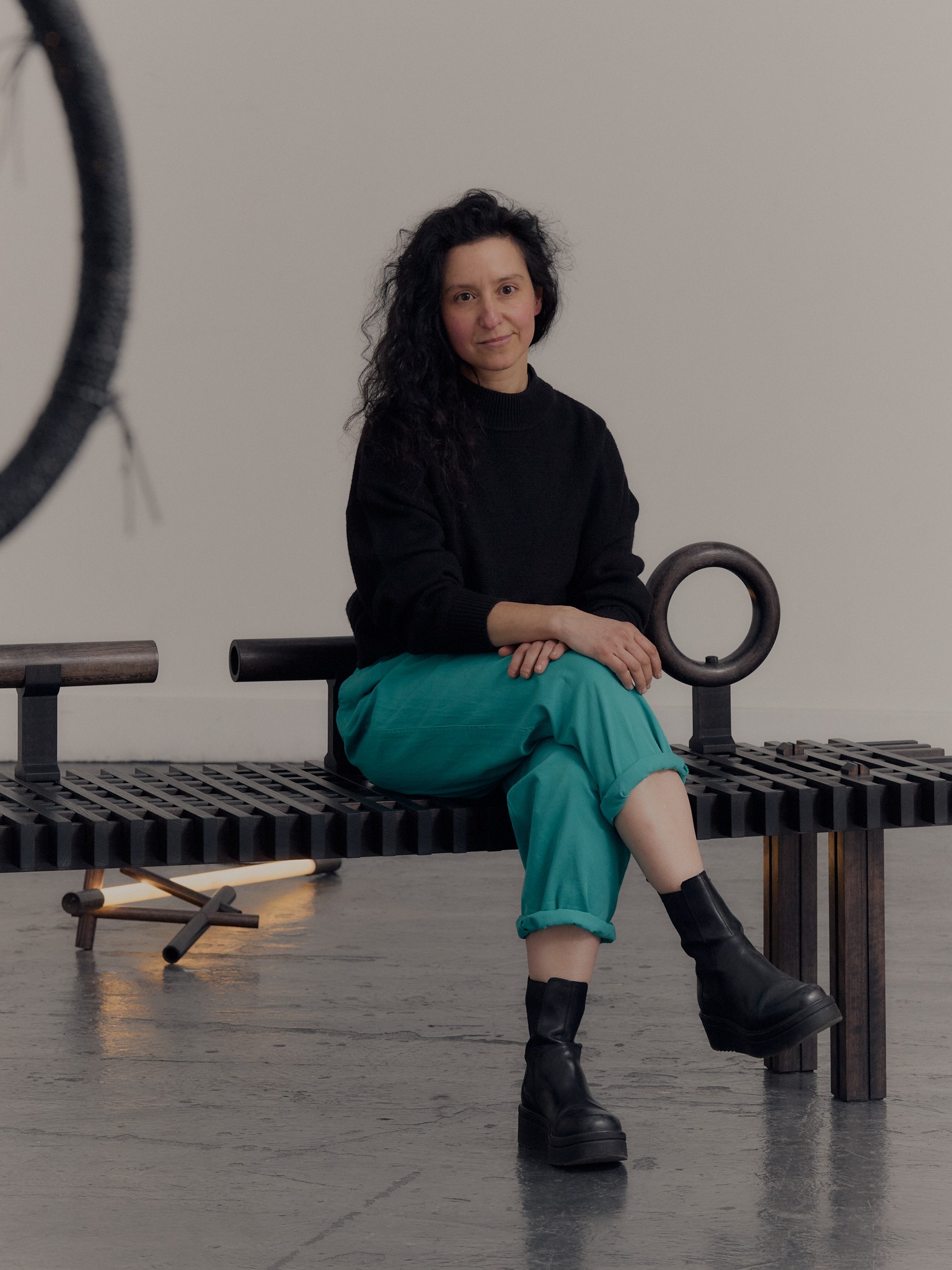 A woman sits on a bench made of wood and rubber.