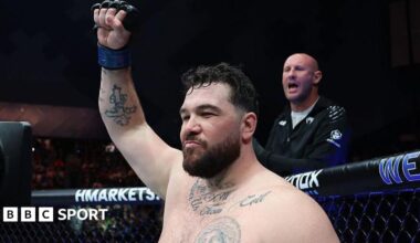 Louie Sutherland holds up his arm as he stands in the octagon