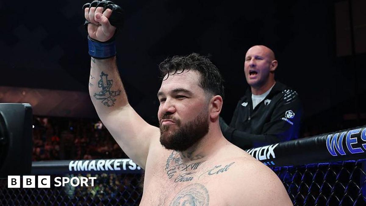 Louie Sutherland holds up his arm as he stands in the octagon