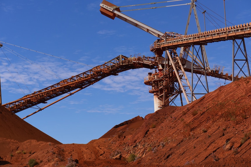 Mining infrastructure and machinery in pits of red dirt.