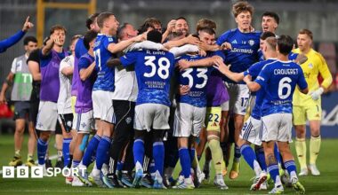 Como players, in blue shirts and socks and white shorts, celebrate in a huddle after securing Champions League qualification