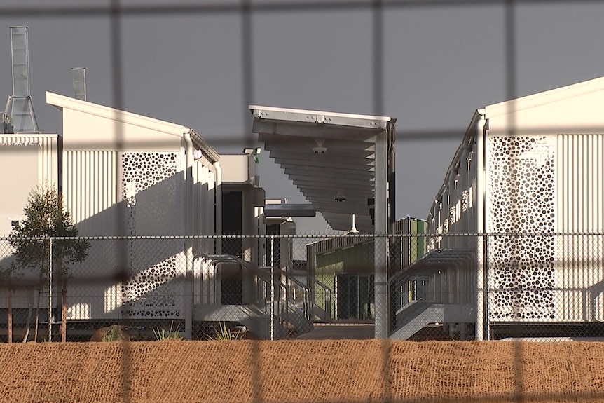 An image of accommodation units shot from behind a wire fence.
