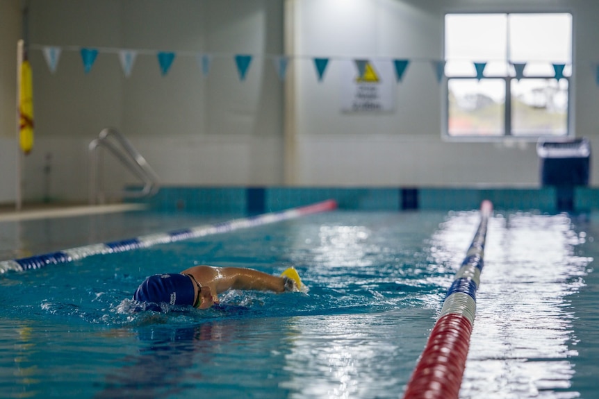 A young woman swimming laps in a pool.