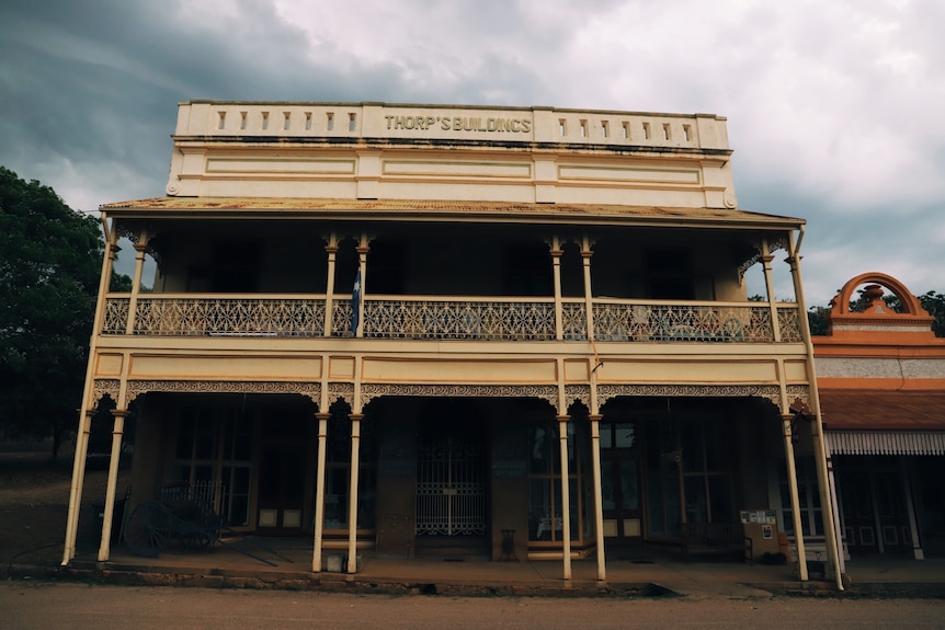 The outside of a hold two-story pub with dark grey skies behind it