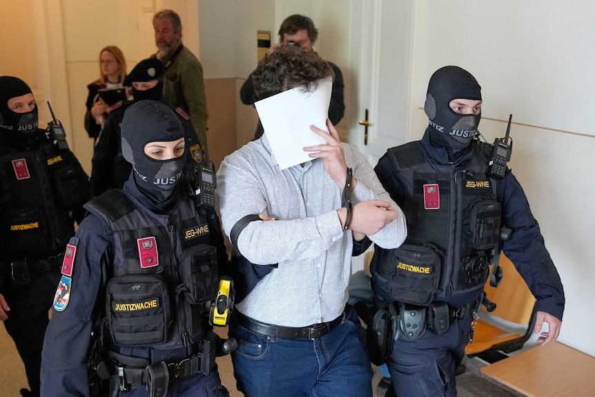 A man covers his face with a sheet of paper.