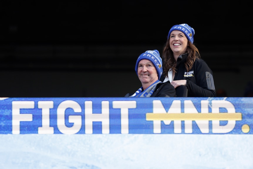 Neale and Bec Daniher smile behind a FightMND banner.