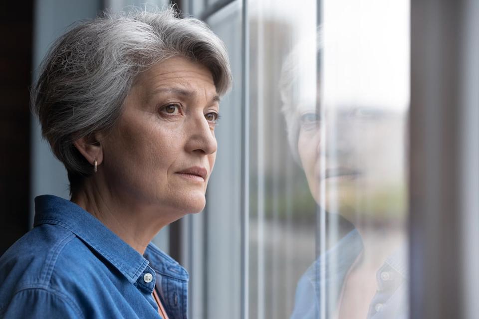 Worried person looking out window.