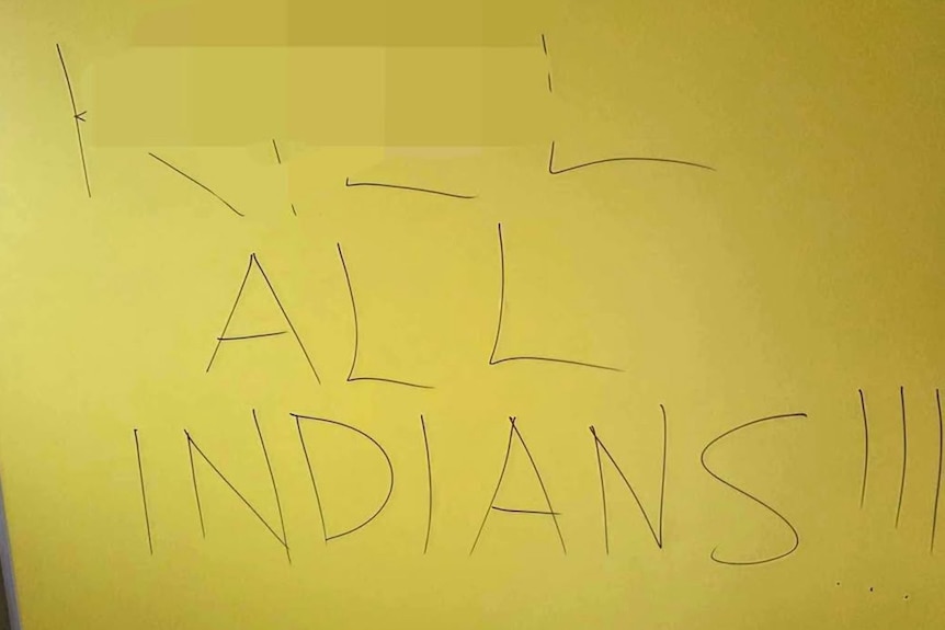 Graffiti on a yellow public bathroom wall