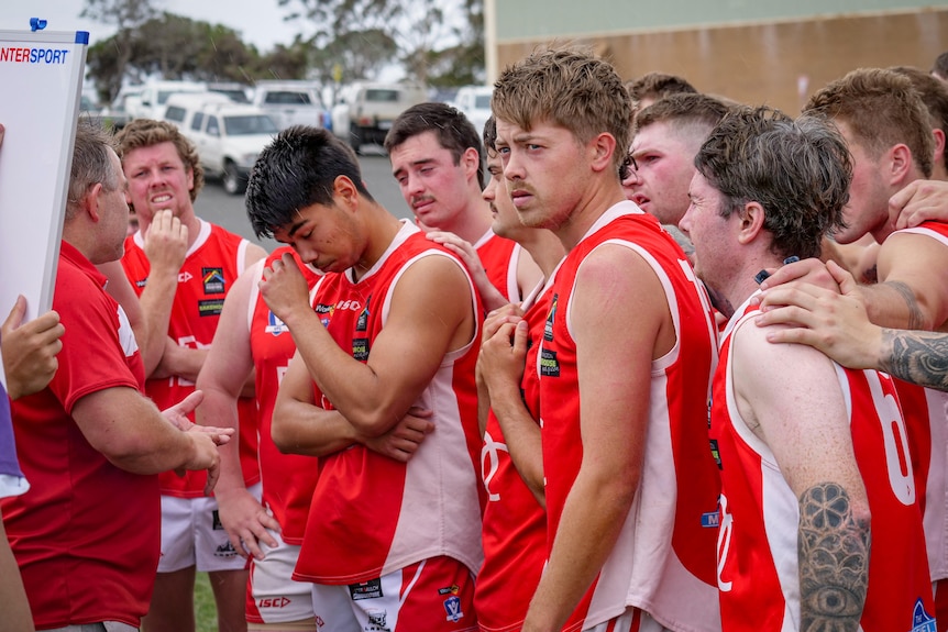 Footballers in a huddle wearing red jumpers