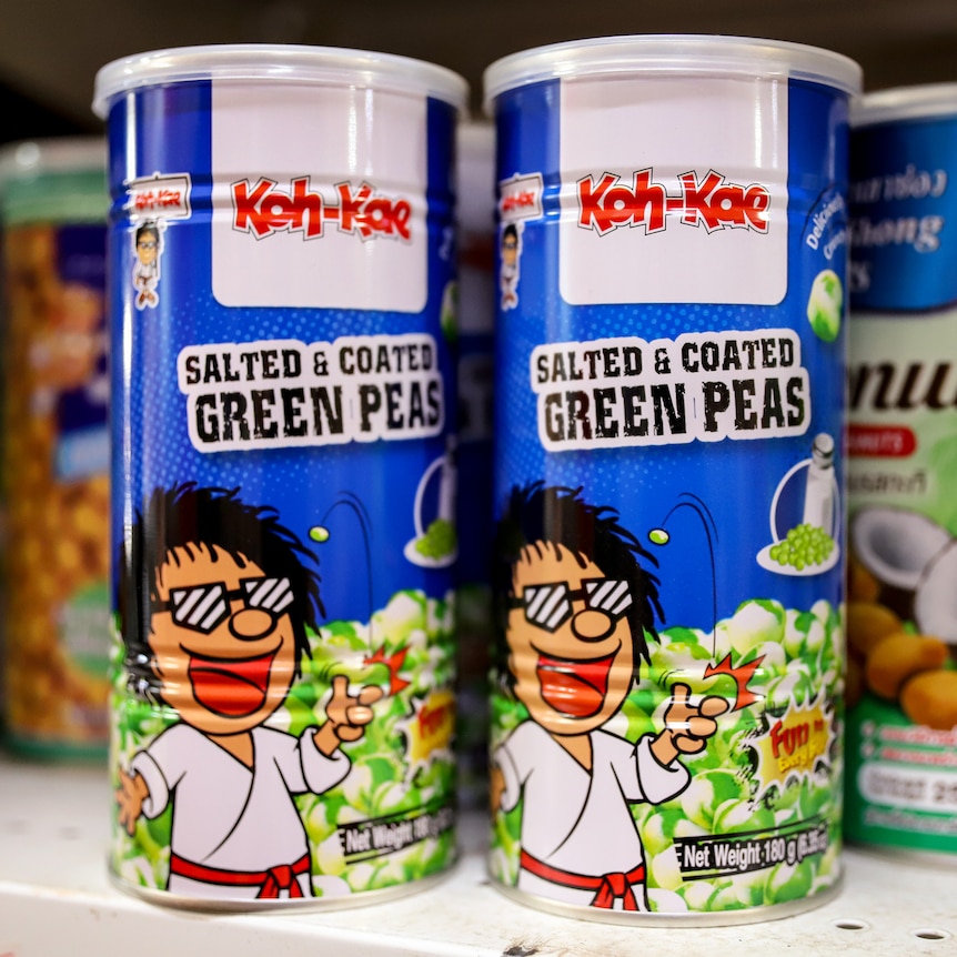 Rows of brightly coloured cans of salted peas for sale on a supermarket shelf
