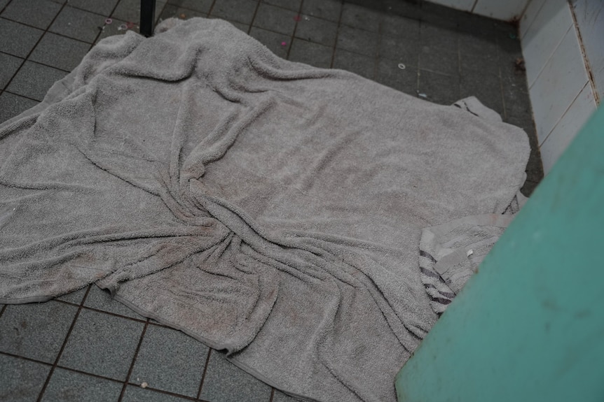 A grey wet towel on tiled floor