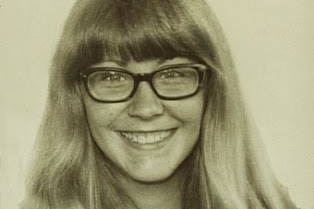 A black and white photo portrait of a smiling girl with glasses