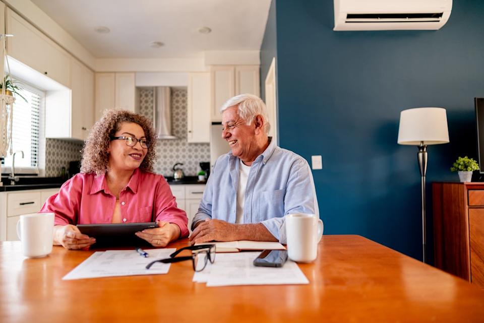 Couple sitting at the dining room table, one holding a tablet.