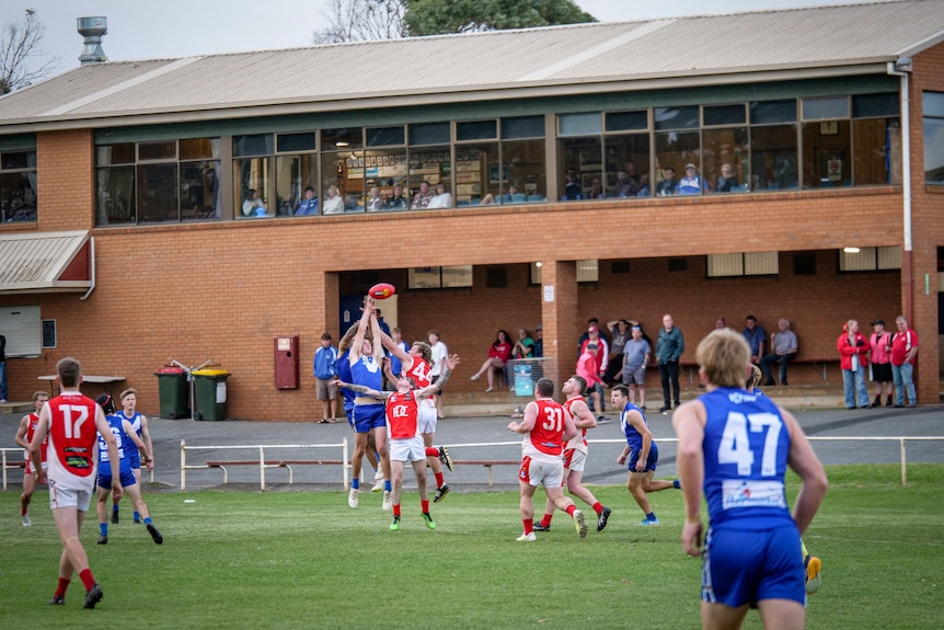 Footballers play in front of a brick grandstand