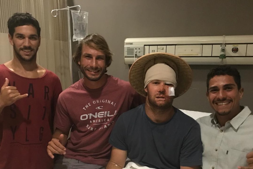 Nathan Bartlett sits in a hospital bed with a bandage over his head and his thump up.