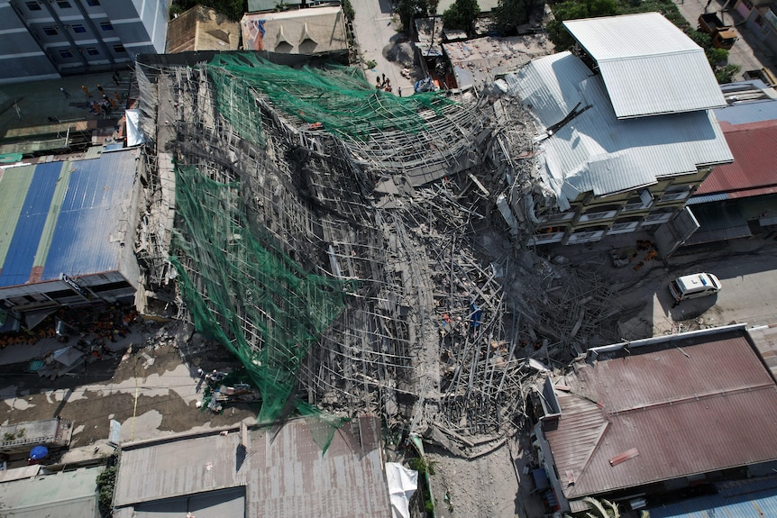 An aerial photo of a pile of debris covered in netting in the middle of a city.