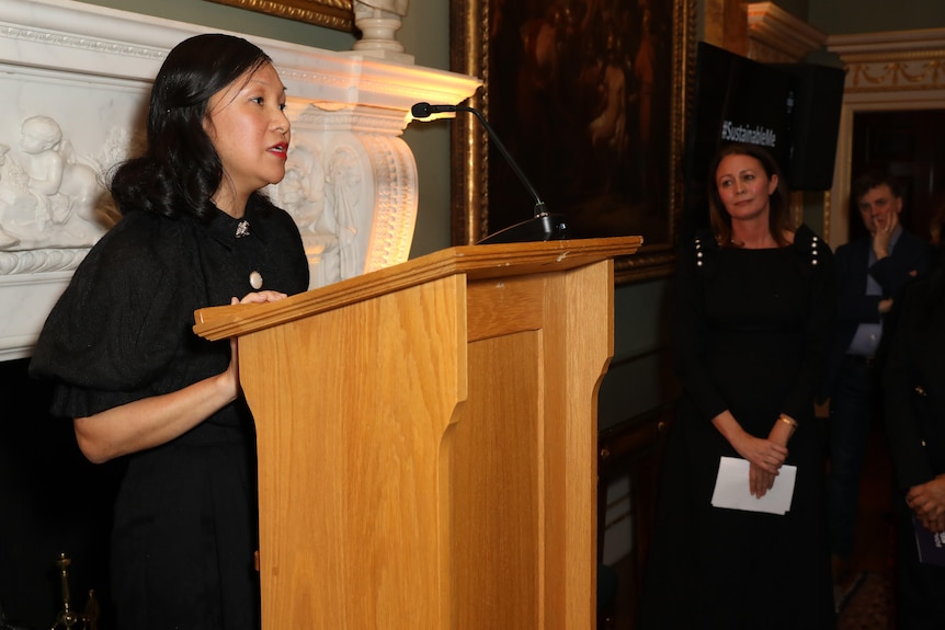 A woman speaking at a rostrum.