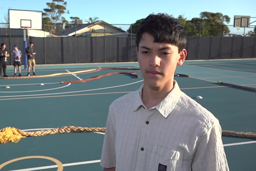 A student standing on a basketball, which has been converted into a race track, with another group of students behind him