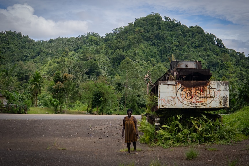 Panguna landowner Beverley Ittamari stands beside abandoned machinery from the old copper and gold mine in Bougainville.