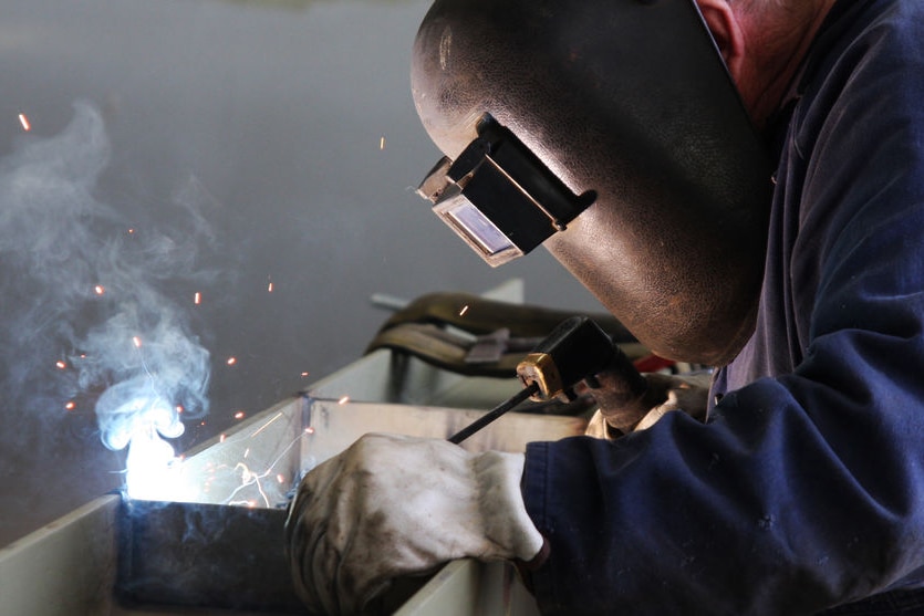 A man in a protective mask using an arc welder