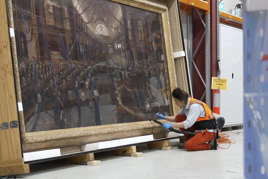 A person brushing a large painting.