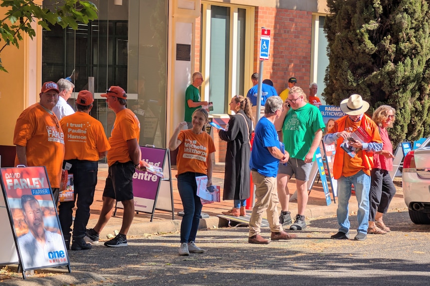 People in coloured t-shirts congregate on the street outside a building.