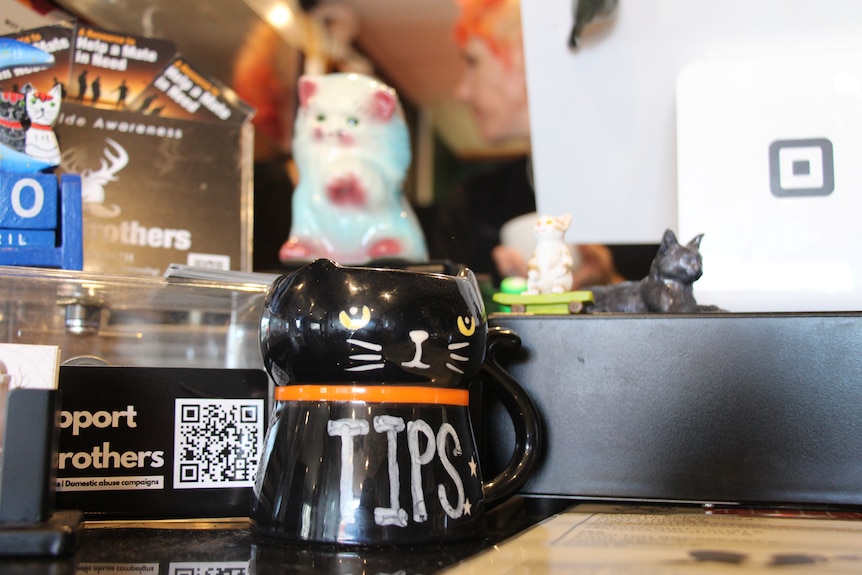 A cat-shaped tip jar with a cafe register