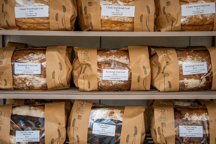 nine loaves of rustic looking bread sit in paper and plastic packaging