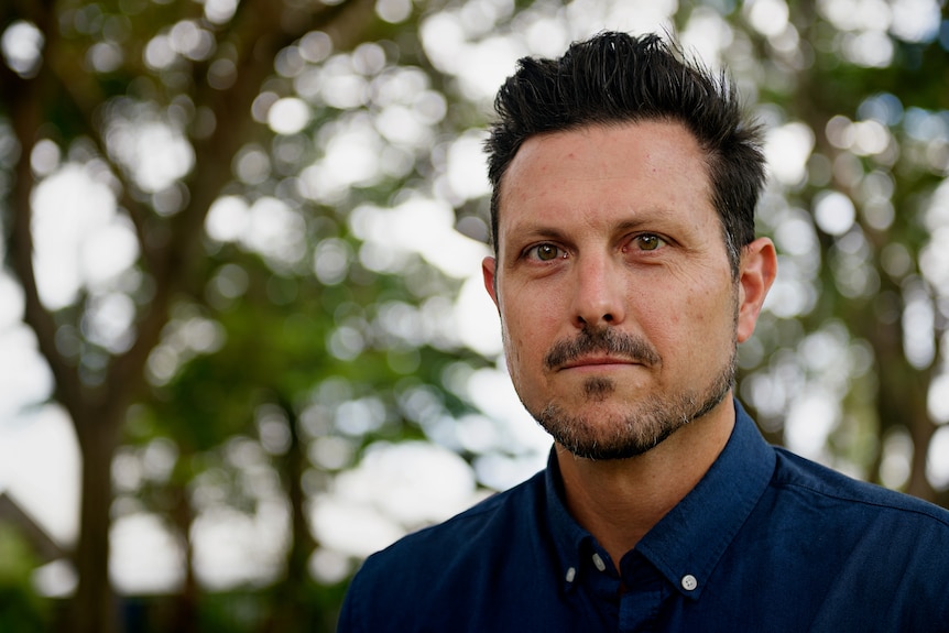 A man looking at the camera, outside