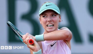 Katie Boulter, wearing a lilac sleeveless top and mint visor, grimaces as she plays a backhand, with her racquet held in two hands over her right shoulder