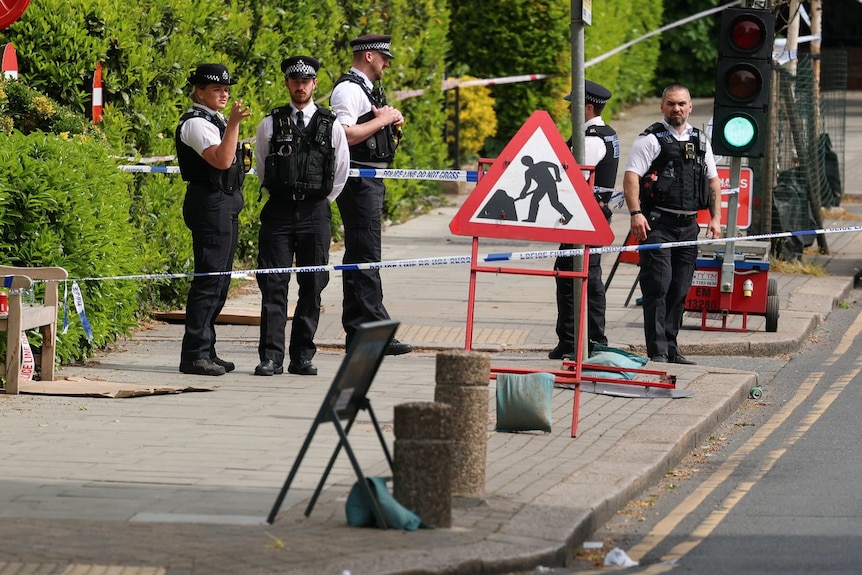 Several police officers standing near a crime scene and looking on.