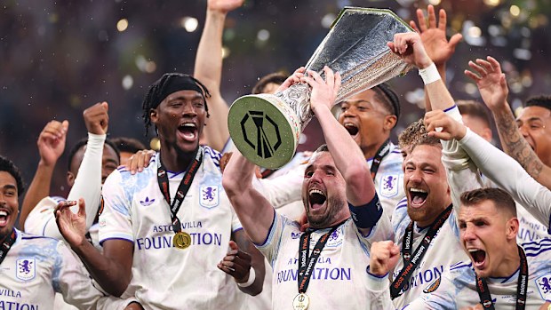 John McGinn of Aston Villa lifts the Europa League trophy with teammates.