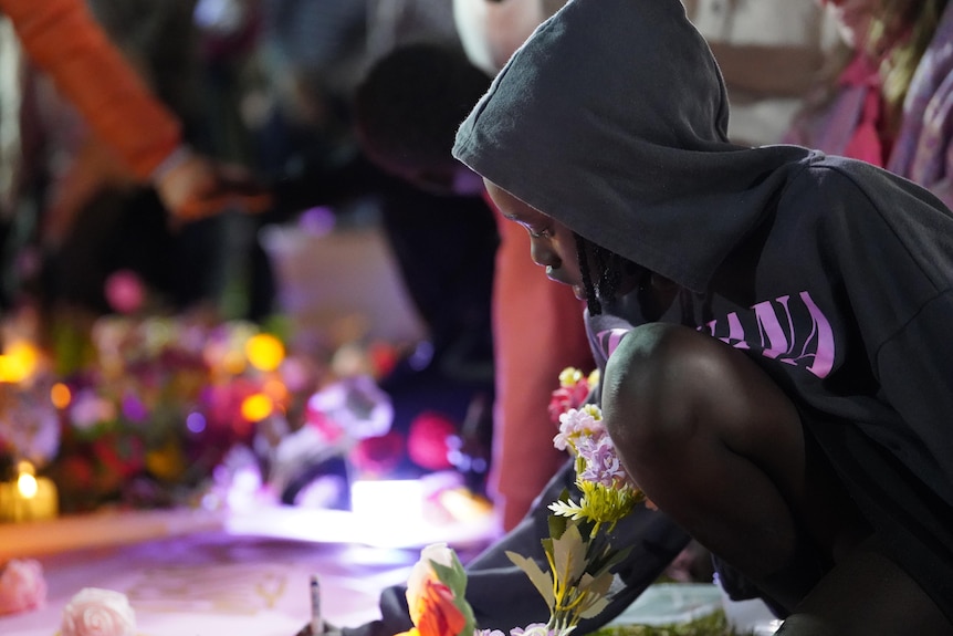 A woman writes on a poster by candlelight
