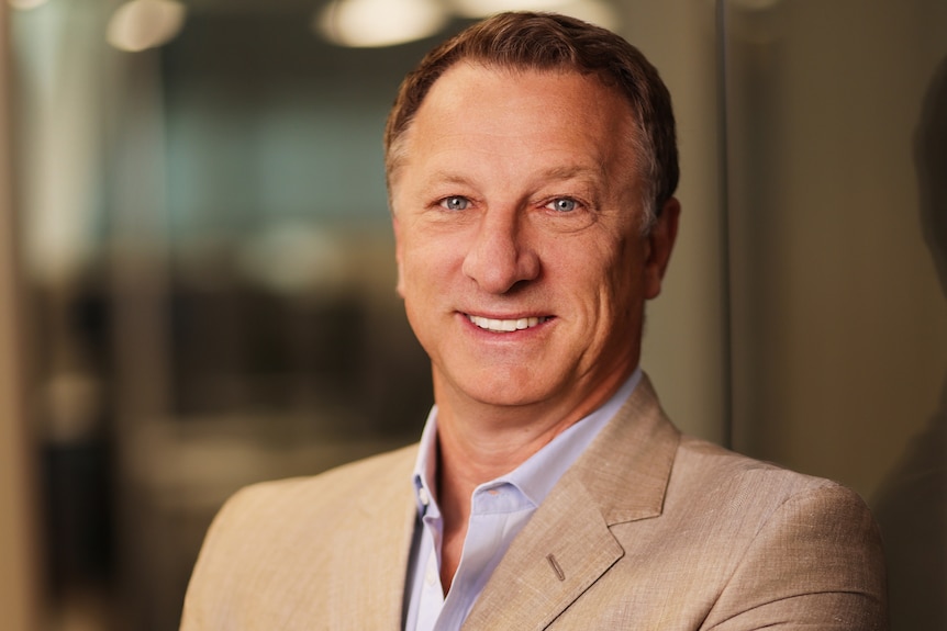 A man smiling in a business suit with his arms crossed
