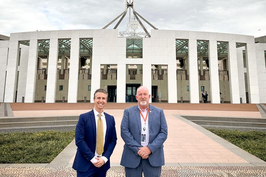 Two men in suits outside parliament house in Canberra.
