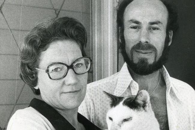 Black and white photo of a couple holding a black and white cat