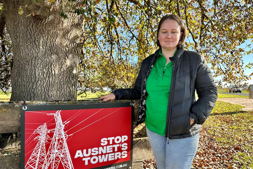 Woman standing beside a sign saying "Stop AusNet's Towers"