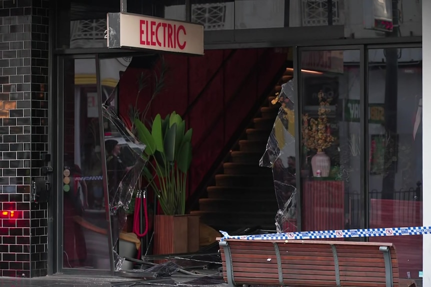 A bar with a broken front window with the sign Electric outside.