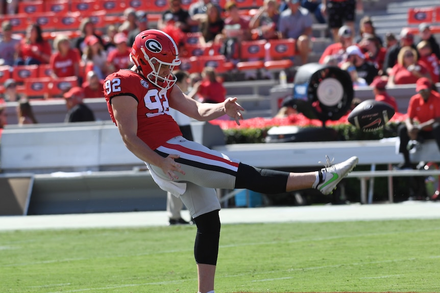 An American football player punts the ball