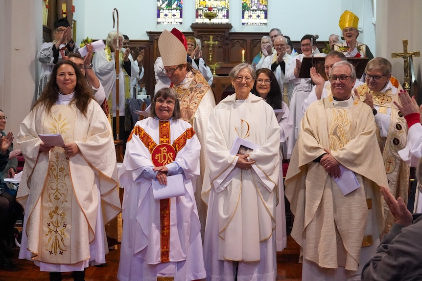 A group of people wearing white and cream-coloured robes in a church