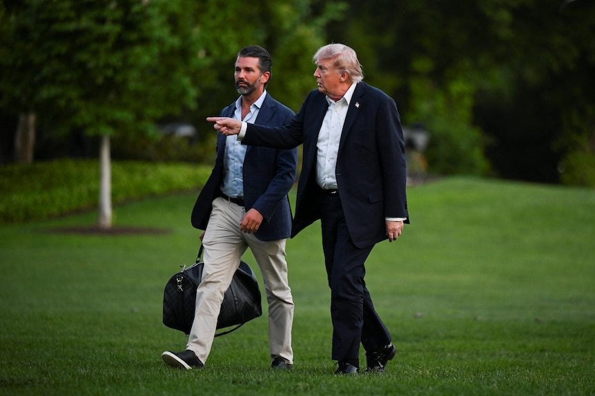 Two men walk across a lawn.