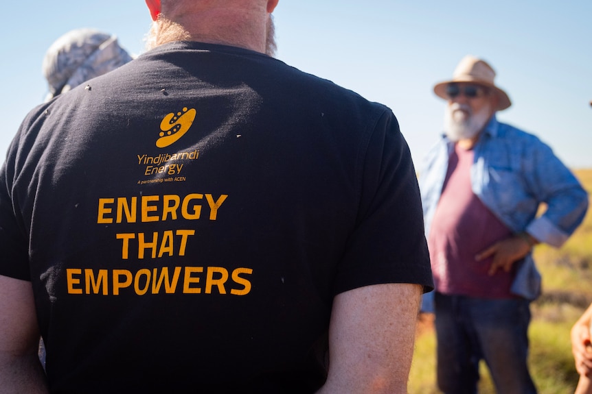 The back of a man in a black shirt with yellow lettering reading "energy that empowers".