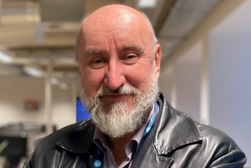 A man in a black jacket smiling at the camera