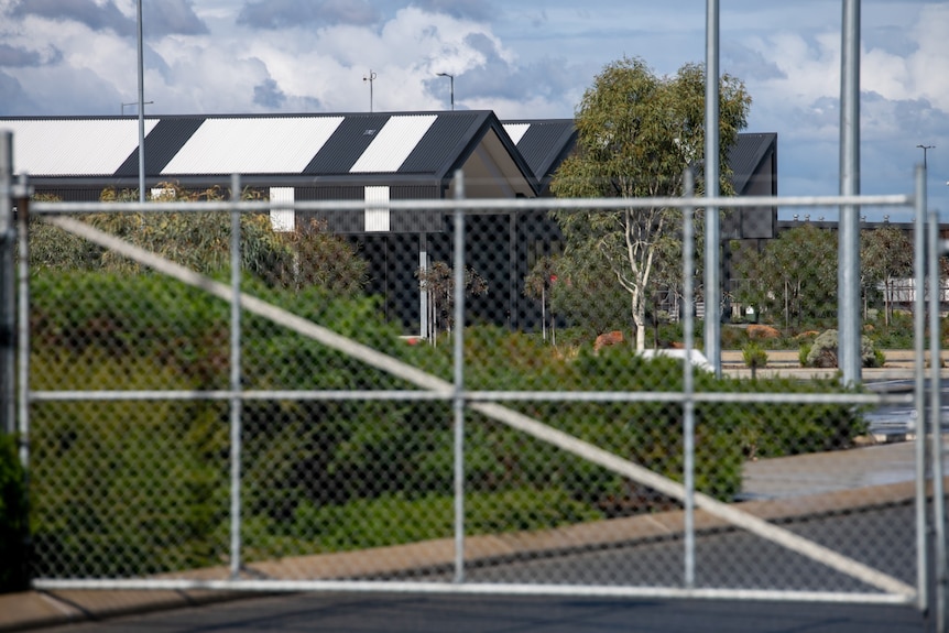 a building with a black and white roof is seen through a fence