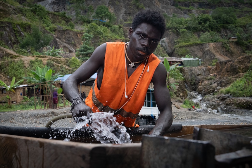 Alluvial miner working while staring down the barrel of the camera.