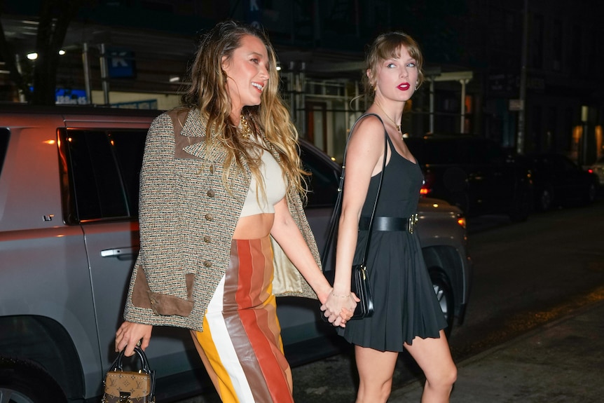 Taylor Swift and Blake Lively walking holding hands on a street